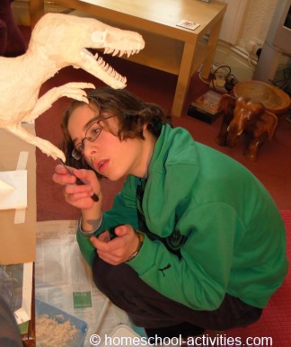 Catherine adding paper mache clay to Velociraptor model